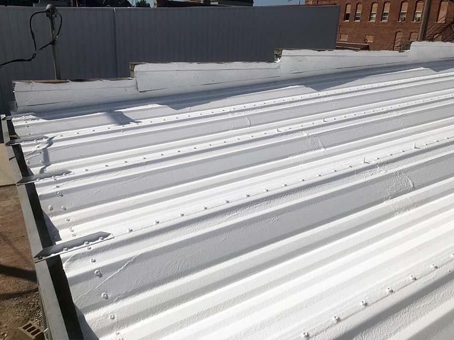 Commercial roof of Clip 'n Curl Hair Design building in Albion, NE, showcasing the result of primer and roof coating system application