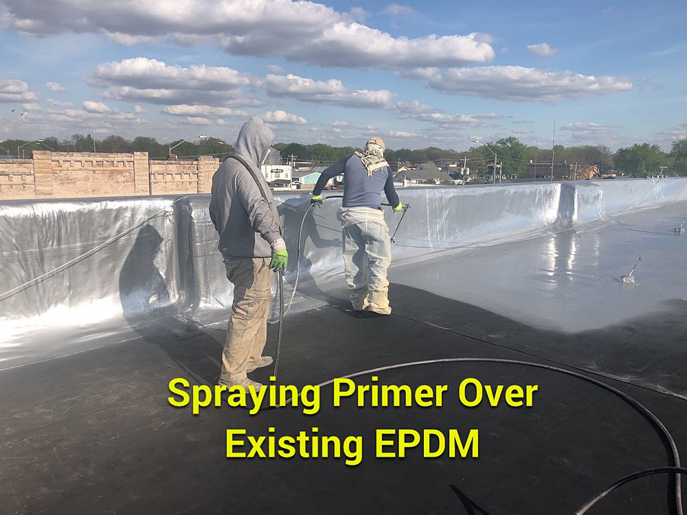 Two roofing contractors spraying primer over the existing EPDM roof in Pierce, NE