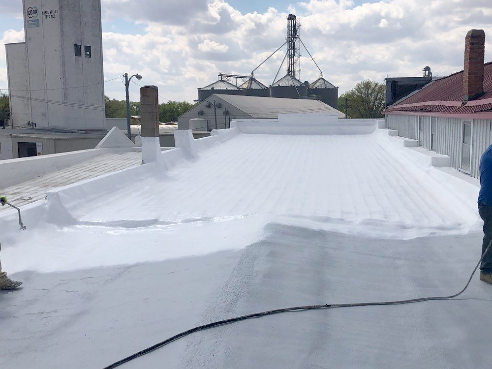 Roofing contractor installing a commercial roofing product with an elastomeric, acrylic, and a monolithic roof coatings